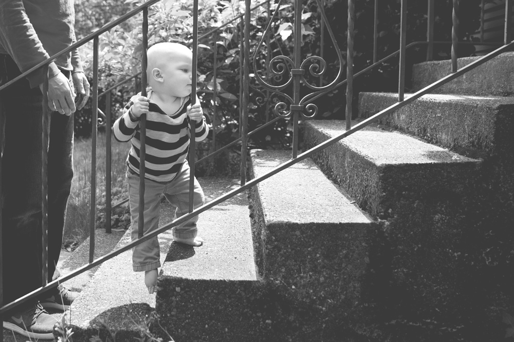 documentary family photography - baby learning to walk up the stairs